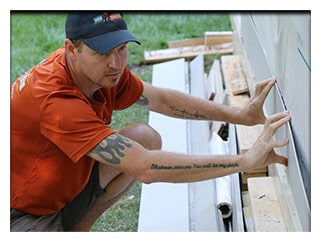 Craftsman Dale repairs cedar siding on a porch.