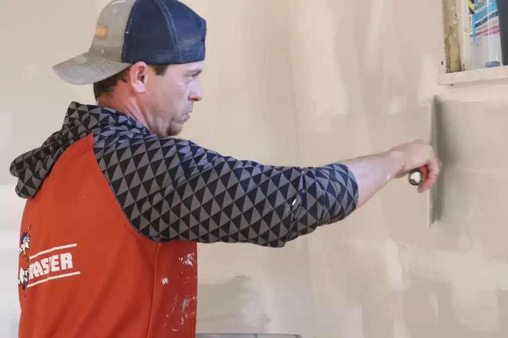 ProMaster craftsman performing drywall repairs near a window in a Cincinnati home.
